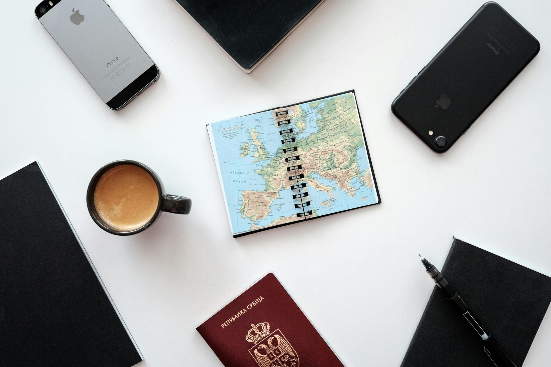 A Map Surrounded with Devices and Cup of Coffee on White Surface