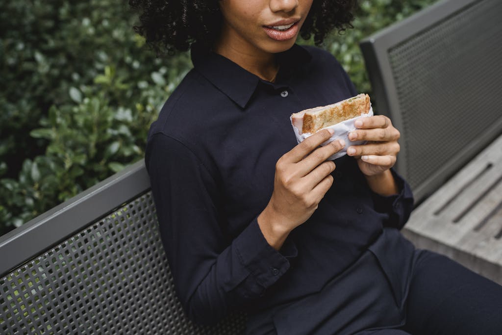 a woman sitting on a bench eating a sandwich