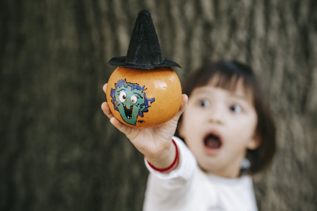 a child holding a pumpkin with a hat on it