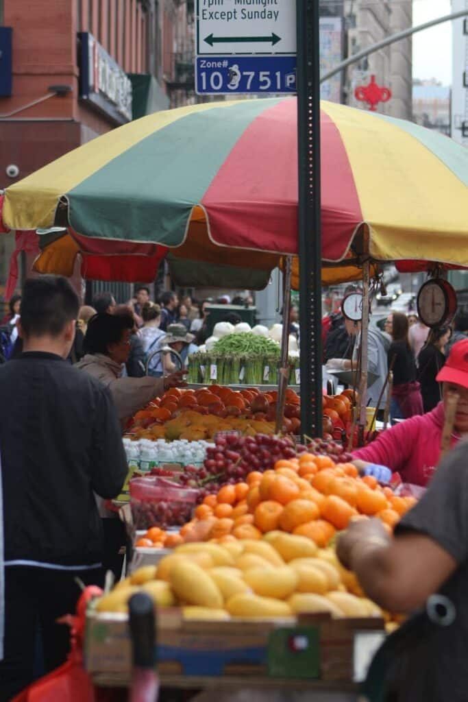 Busy street market in Kensington Market Toronto with food stalls and people shopping under colorful umbrellas