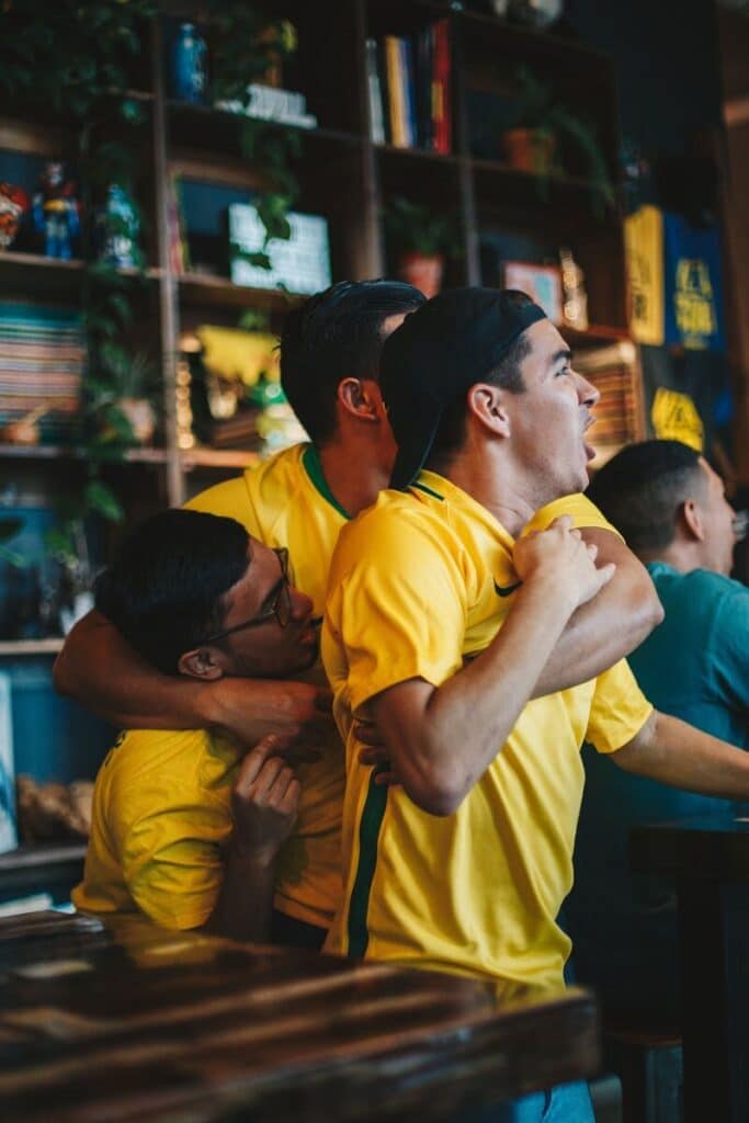 How to Plan a Last-Minute World Cup 2026 Trip (8-Week Countdown) 2 Football fans celebrating and watching a match together in a sports bar