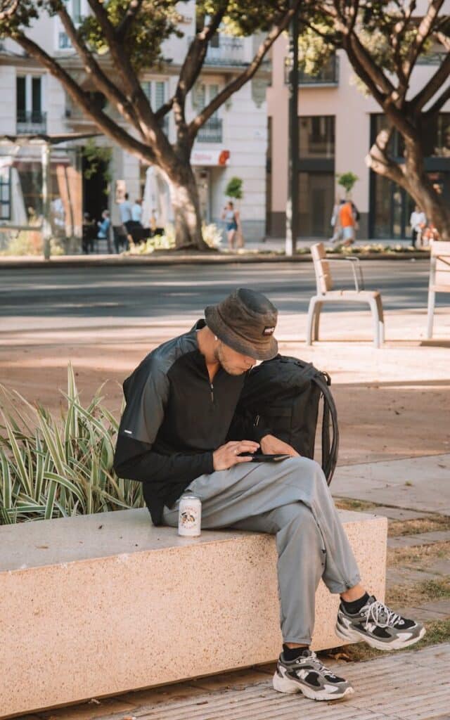 traveler sitting on bench using smartphone mobile data in Spain