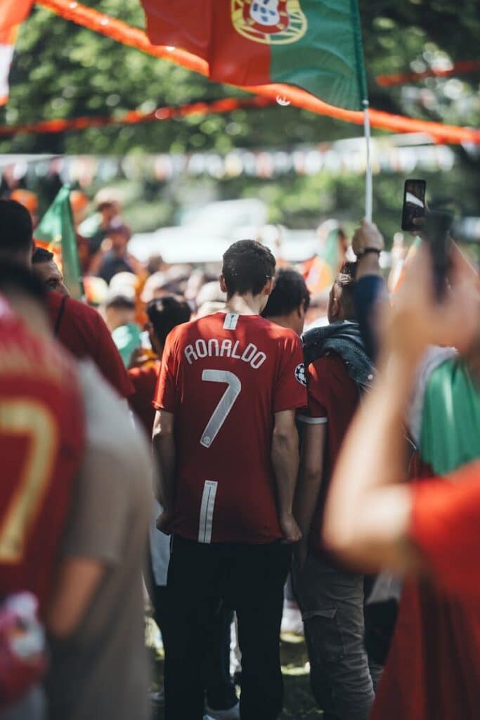 Football fans gathered closely together wearing jerseys and waving flags