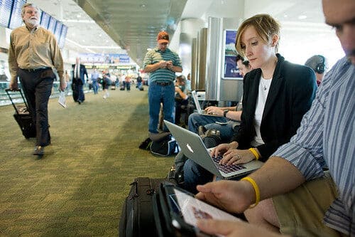 People using laptop and phone on public WiFi in airport