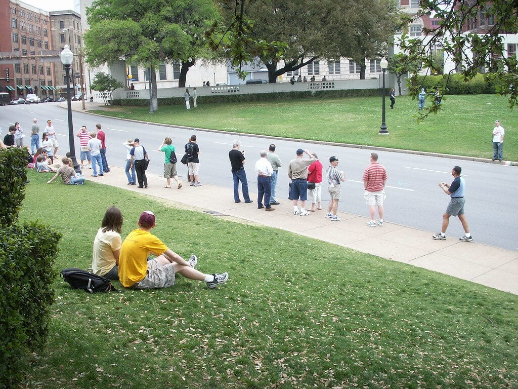 Top Things to Do in Dallas During the World Cup 2026 5 Visitors standing at Dealey Plaza in Dallas near the grassy knoll, overlooking the JFK assassination site