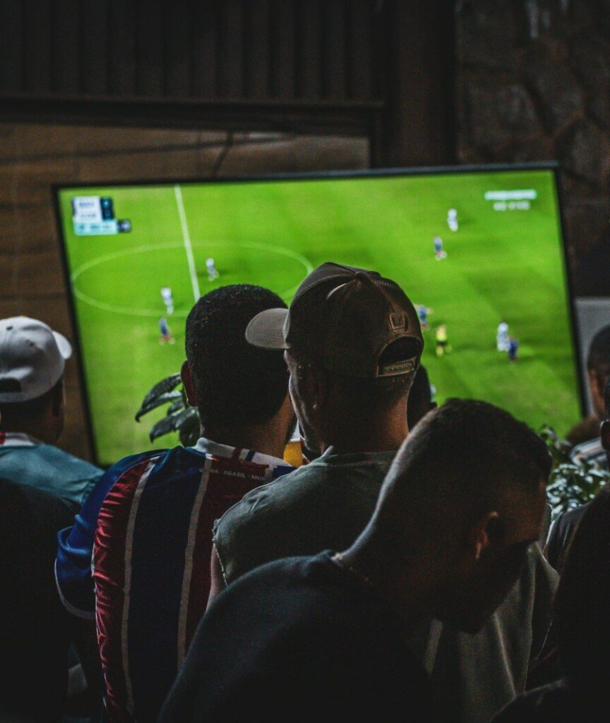 Fans watching a football match on large screens in a crowded sports bar