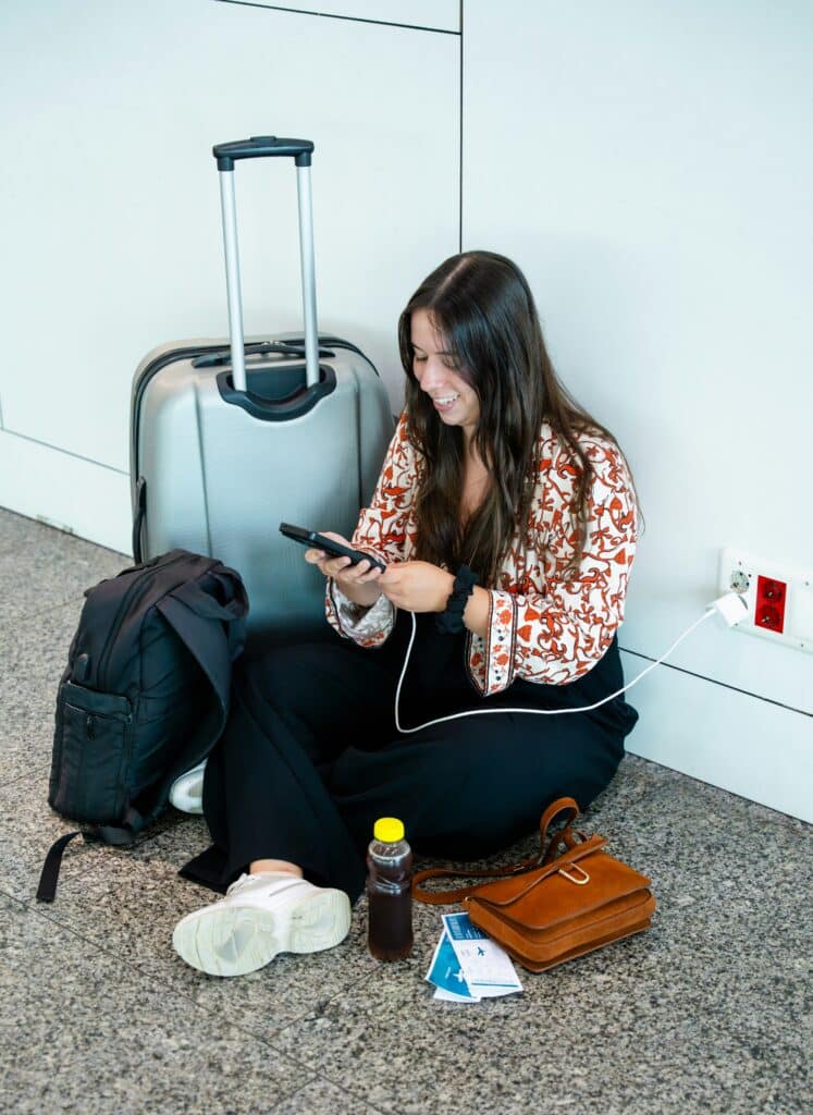 Traveller sitting at the airport using her phone and charging devices during the World Cup 2026 Travel Guide