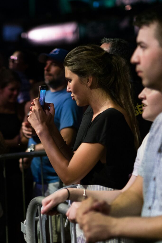 Uber vs Public Transport for World Cup 2026? Avoid Surge Pricing and Overpriced Stadium Trains 2 Person checking their phone in a crowded stadium environment while trying to arrange transport after an event