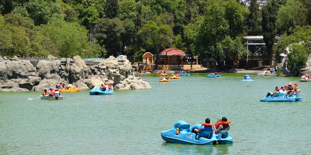 People boating on Chapultepec Lake in Mexico City surrounded by trees and park scenery