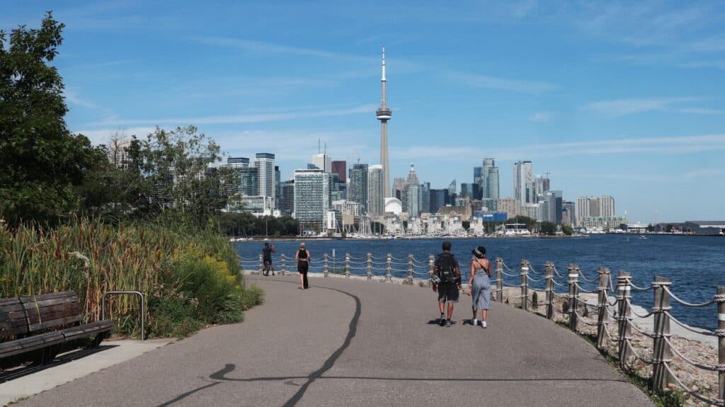People walking along the Toronto waterfront with views of the CN Tower and skyline