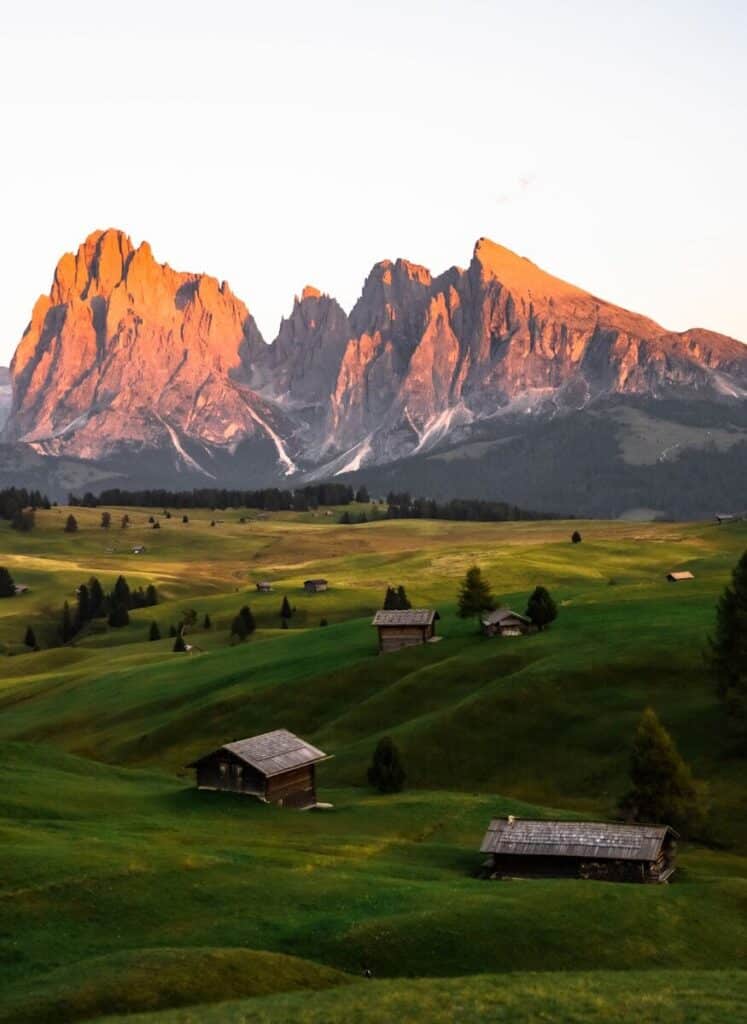 Mountain landscape in the Dolomites with alpine huts and green fields
