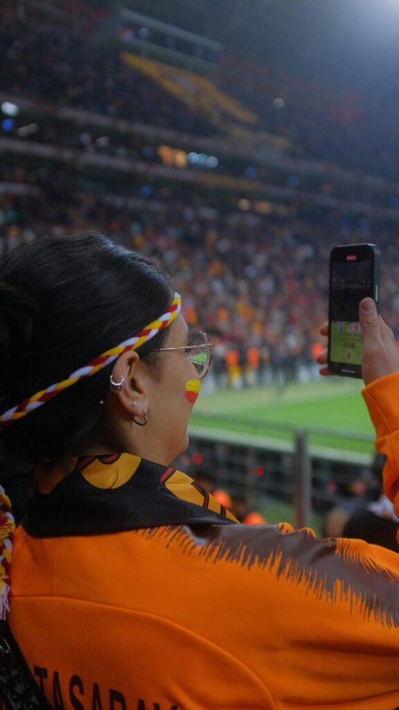 Woman checking her phone in a crowded stadium area — staying aware of surroundings in busy environments