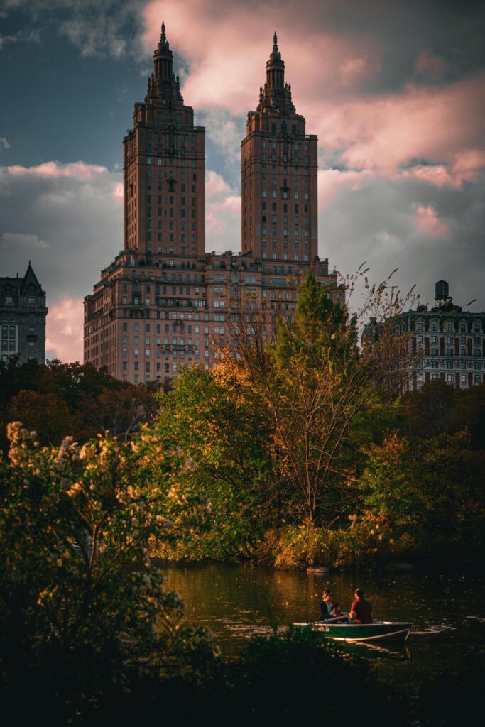 People boating on a lake in Central Park with New York skyline in the background