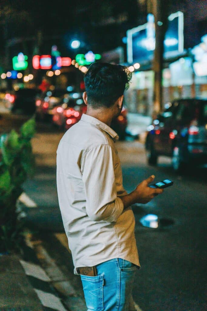 Traveller using a smartphone on a city street at night while staying connected abroad