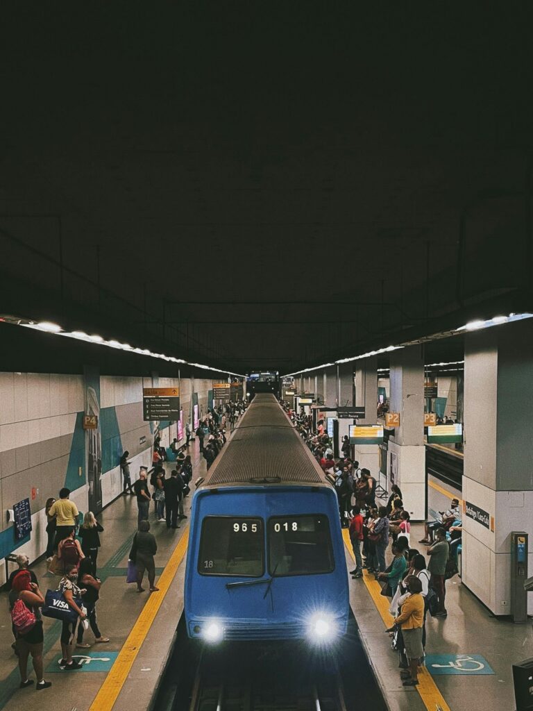 Busy metro station with train arriving and passengers waiting on the platform in a large city
