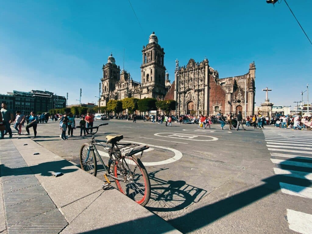 Metropolitan Cathedral in Mexico City at Zócalo square with people walking across the plaza