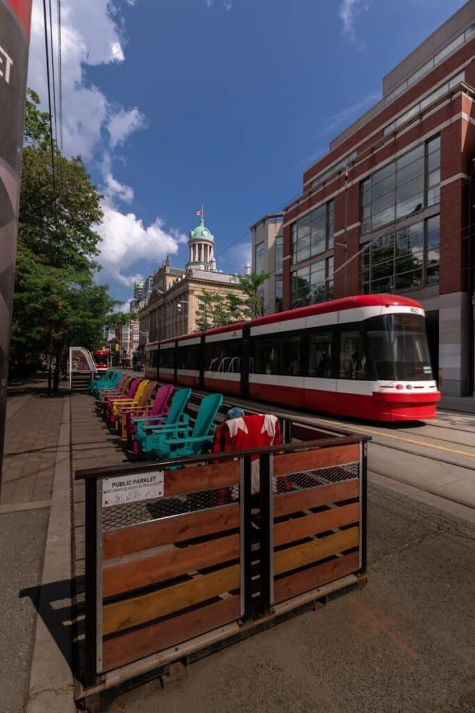 Toronto streetcar passing through downtown with outdoor seating and city buildings