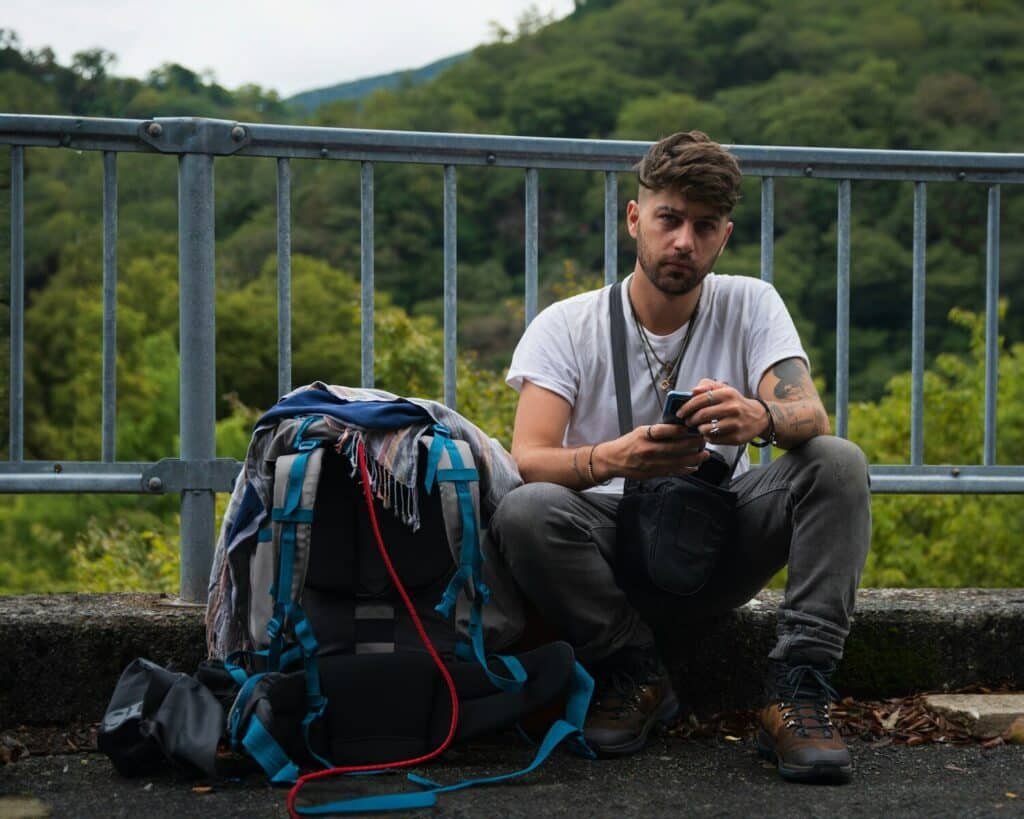 World Cup 2026 Travel Tips: What Most Guides Won't Tell You 16 Traveler charging phone while sitting with backpack outdoors