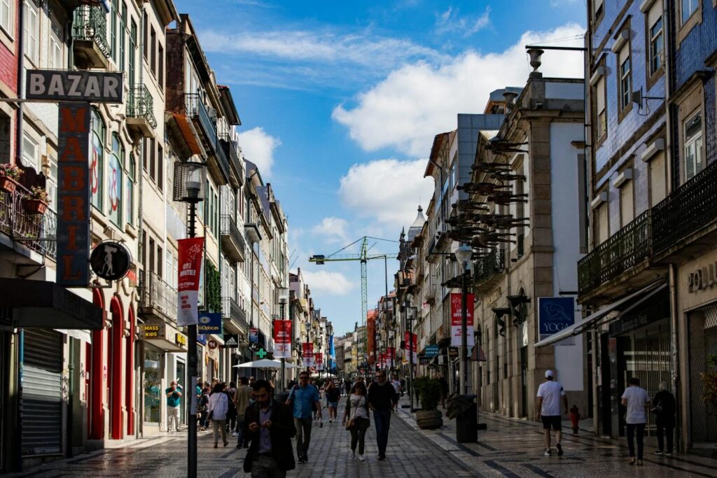 eSIM Portugal vs Roaming: Best Way to Stay Connected as a Traveler in 2026 5 busy shopping street in Porto with pedestrians and colourful storefronts on a sunny day