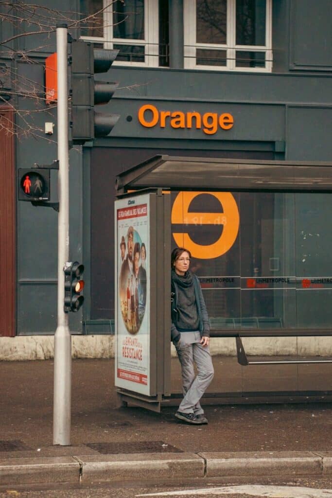 eSIM or Physical SIM in France? Pros, Cons & Best Pick for Travellers 2026 3 Orange mobile store in Paris with woman standing at bus stop outside