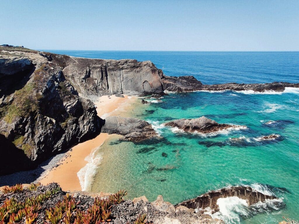 eSIM Portugal vs Roaming: Best Way to Stay Connected as a Traveler in 2026 9 dramatic Alentejo coastline with golden sandy beach and turquoise sea viewed from cliff top
