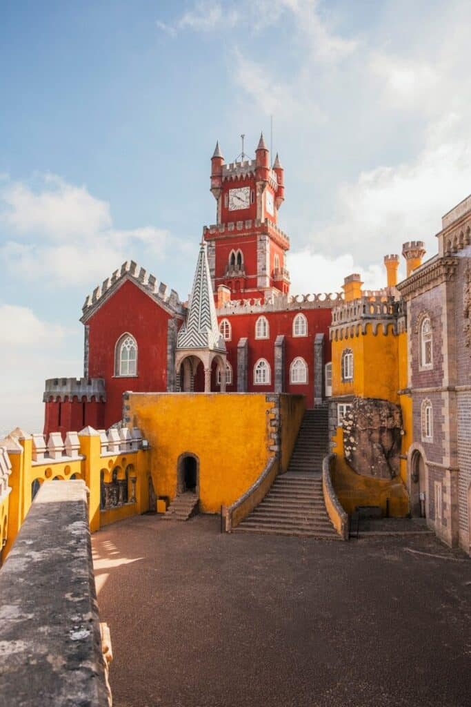 eSIM Portugal vs Roaming: Best Way to Stay Connected as a Traveler in 2026 10 colourful Pena Palace in Sintra with red and yellow towers against a blue sky