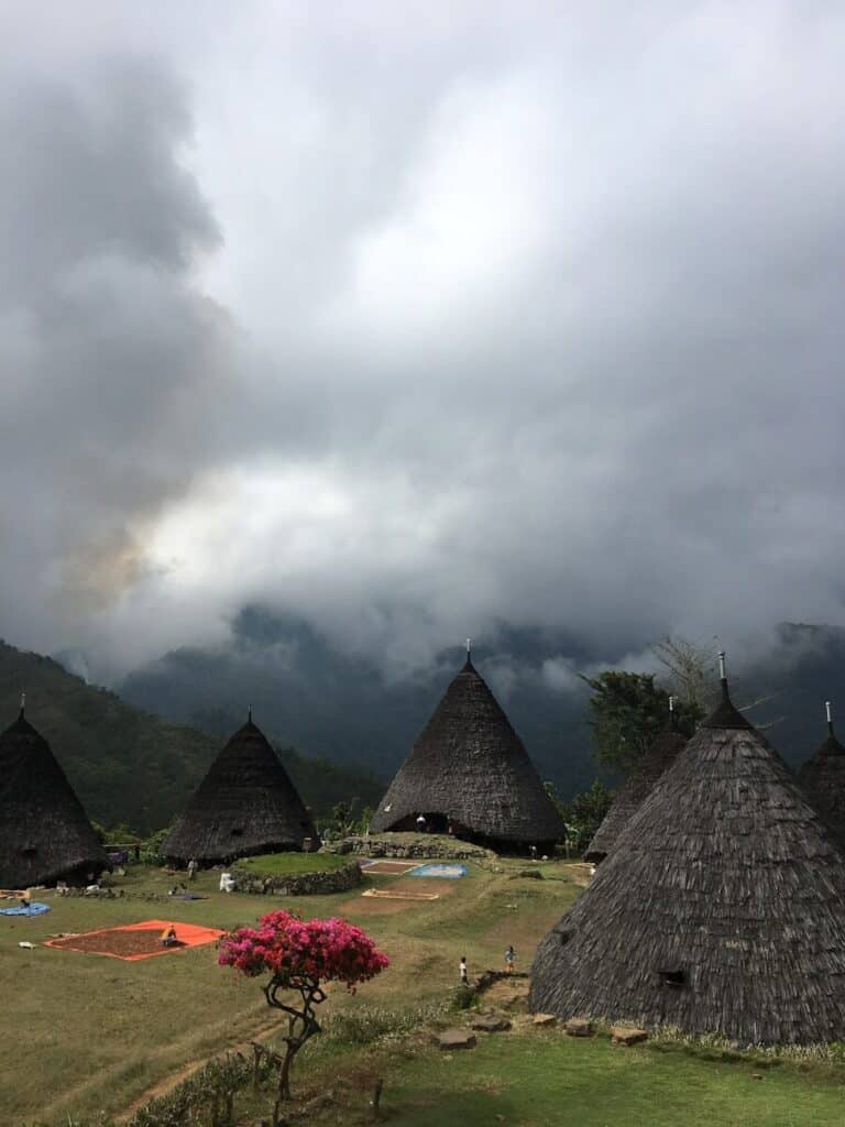 traditional cone-shaped thatched huts of Wae Rebo village in Flores Indonesia under dramatic cloudy skies