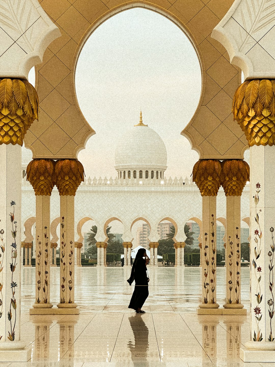 woman walking through a grand mosque courtyard in Abu Dhabi