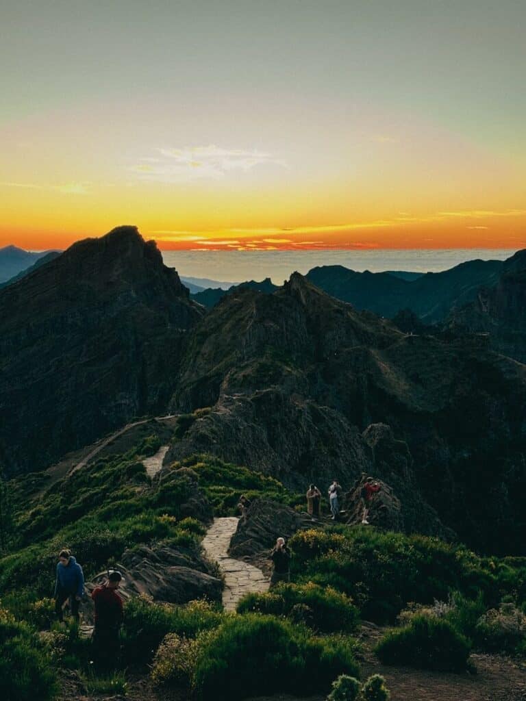 eSIM Portugal vs Roaming: Best Way to Stay Connected as a Traveler in 2026 11 hikers on a mountain ridge in Madeira at sunset with orange sky and rocky peaks