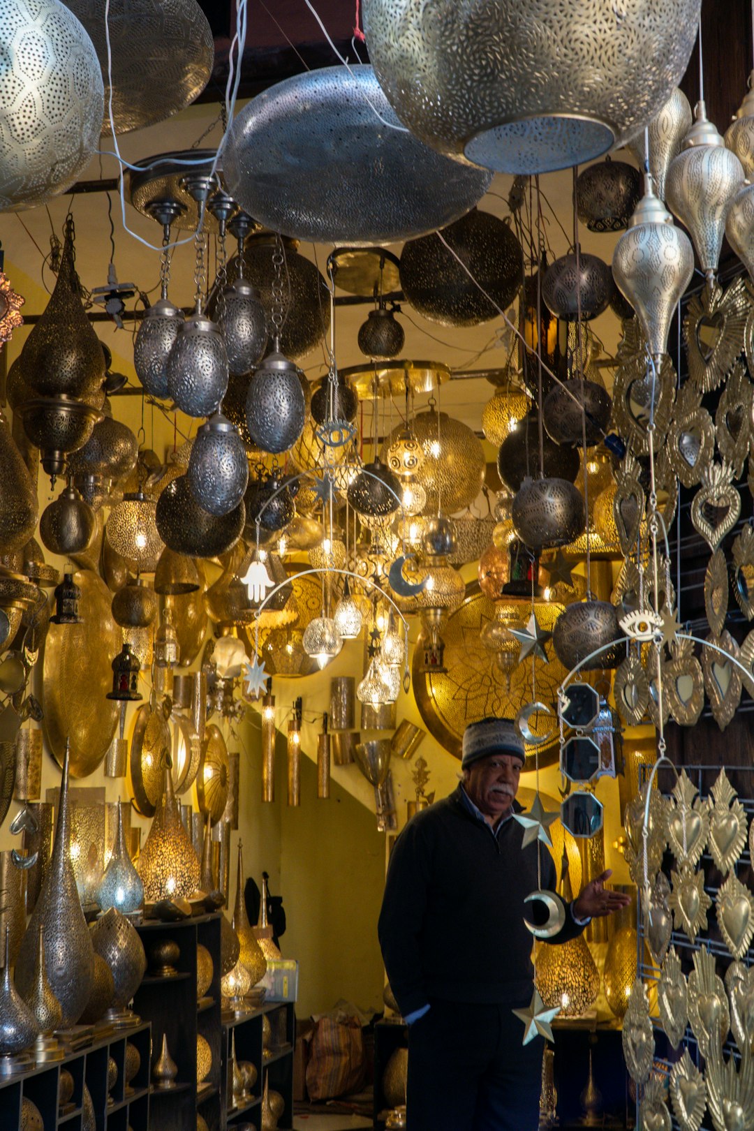 man standing in a shop filled with ornate metal lamps in Morocco