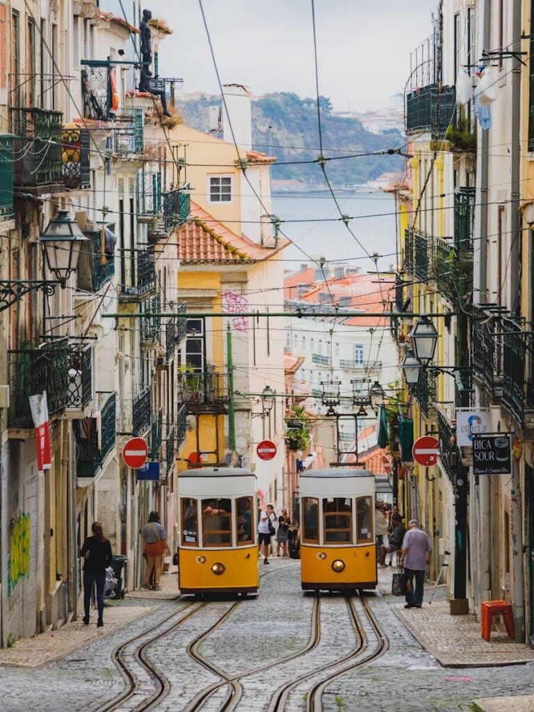 eSIM Portugal vs Roaming: Best Way to Stay Connected as a Traveler in 2026 6 two yellow trams on a steep cobblestone street in Lisbon with colourful buildings