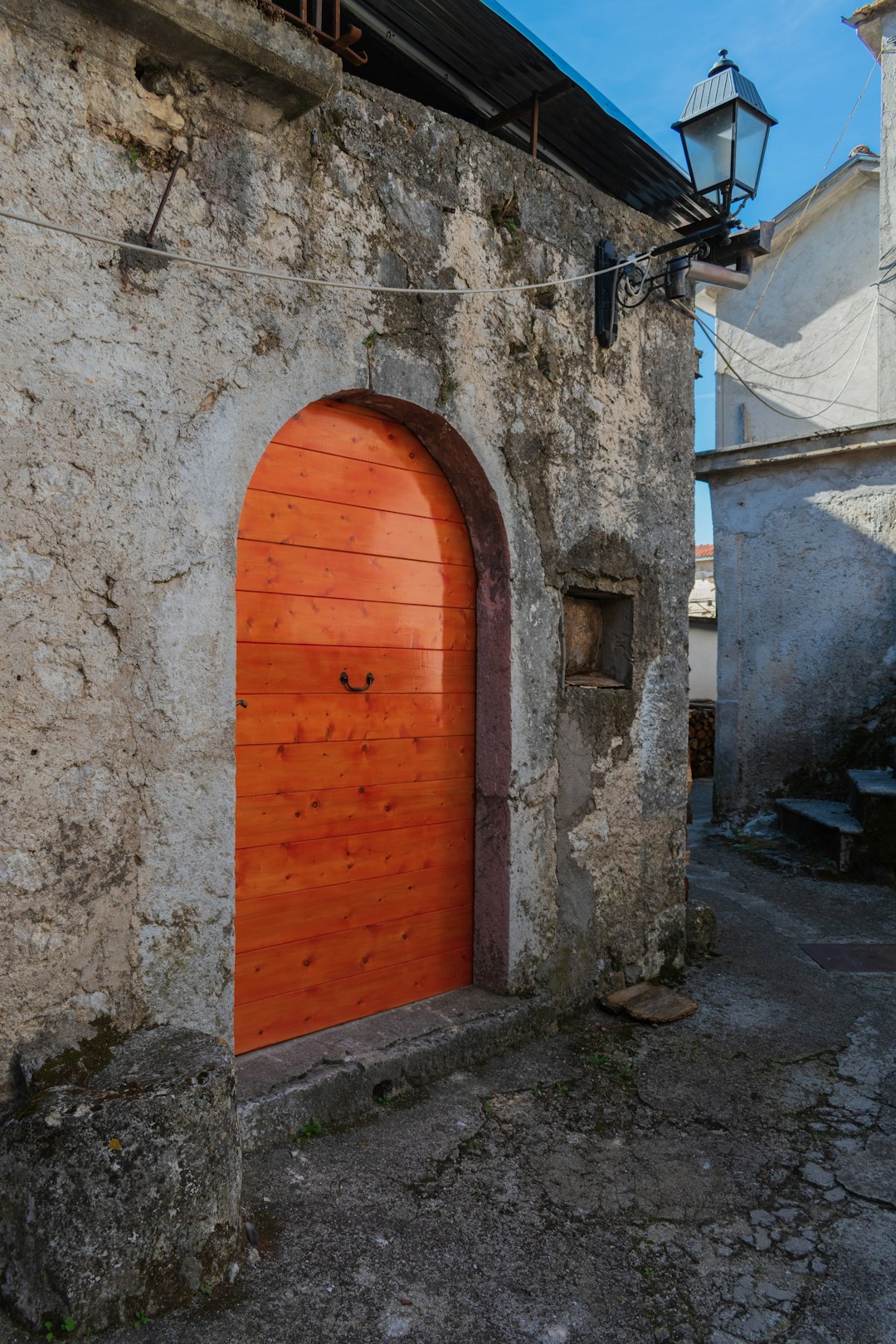 Arched orange wooden door set into a stone building