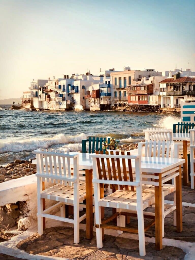 waterfront tables and chairs in Little Venice Mykonos with whitewashed buildings on the sea edge