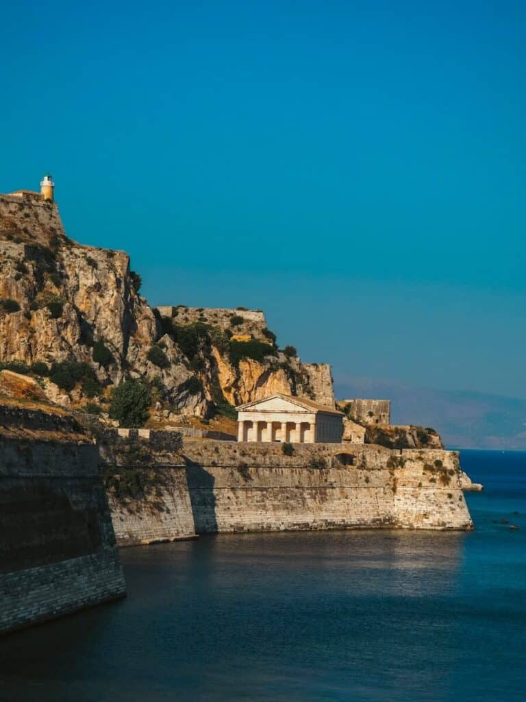 Old Fortress of Corfu on a rocky promontory with a Greek temple and lighthouse above the sea