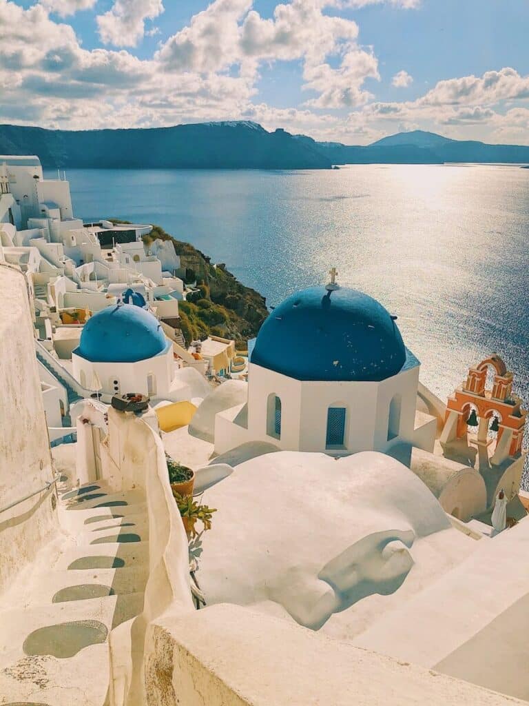 white buildings and blue domed churches in Santorini overlooking the caldera and sea