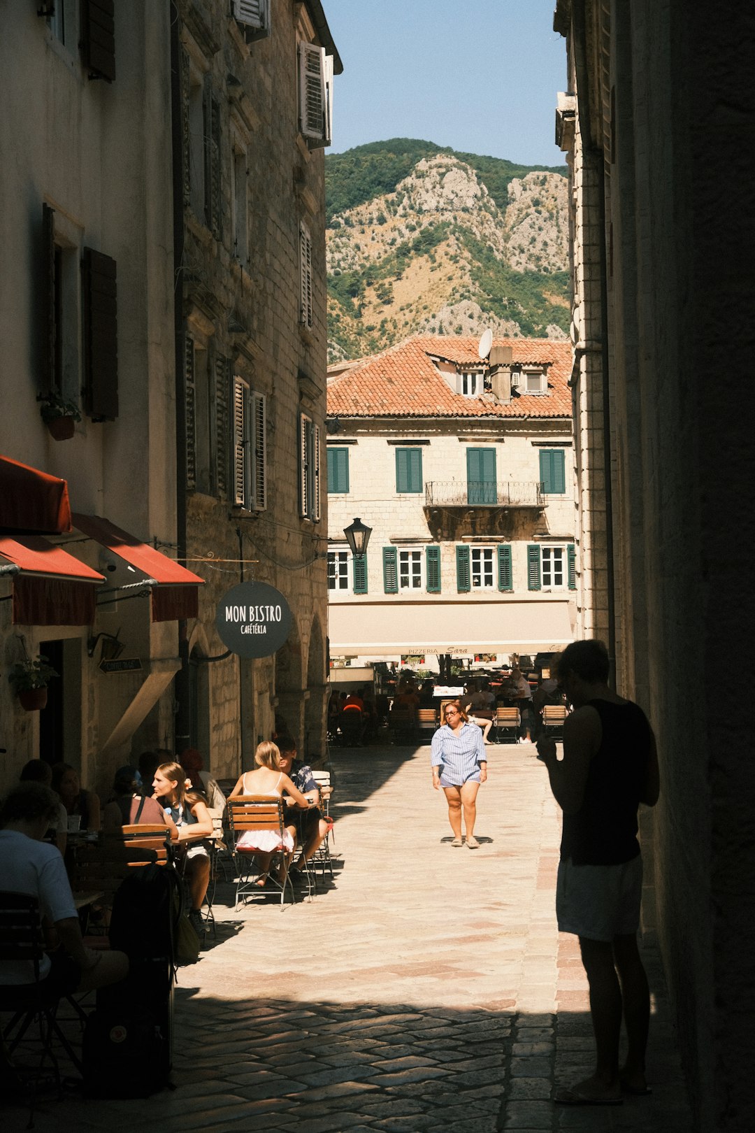 People dine at an outdoor cafe on a cobblestone street in Europe