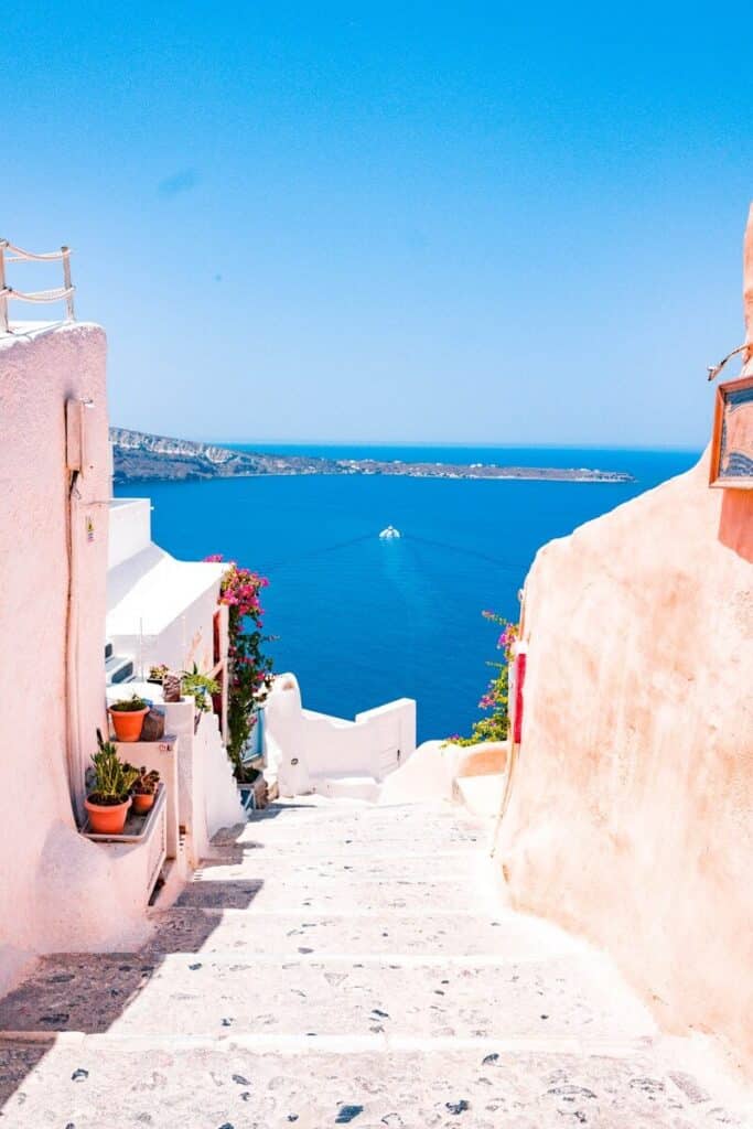 narrow whitewashed stairway in Santorini leading down to the deep blue caldera
