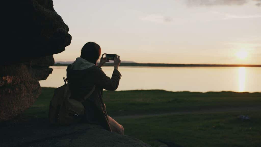 young backpacker photographing a landscape while traveling in Canada
