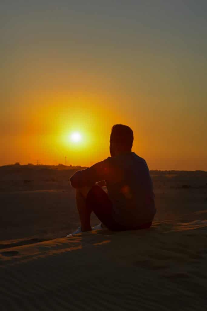 Traveler sitting on a sandy dune outside Dubai