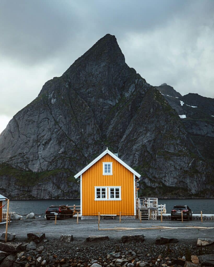 A traditional fishing village sits beneath towering mountains in Lofoten