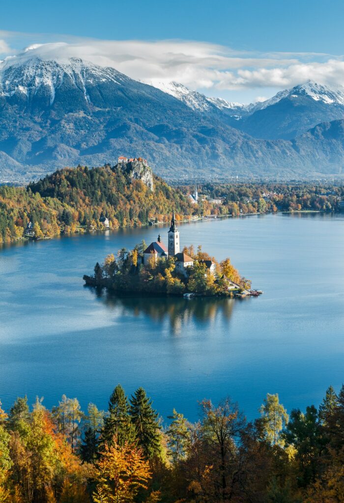 A small island with a building sits ringed by mountains in Slovenia