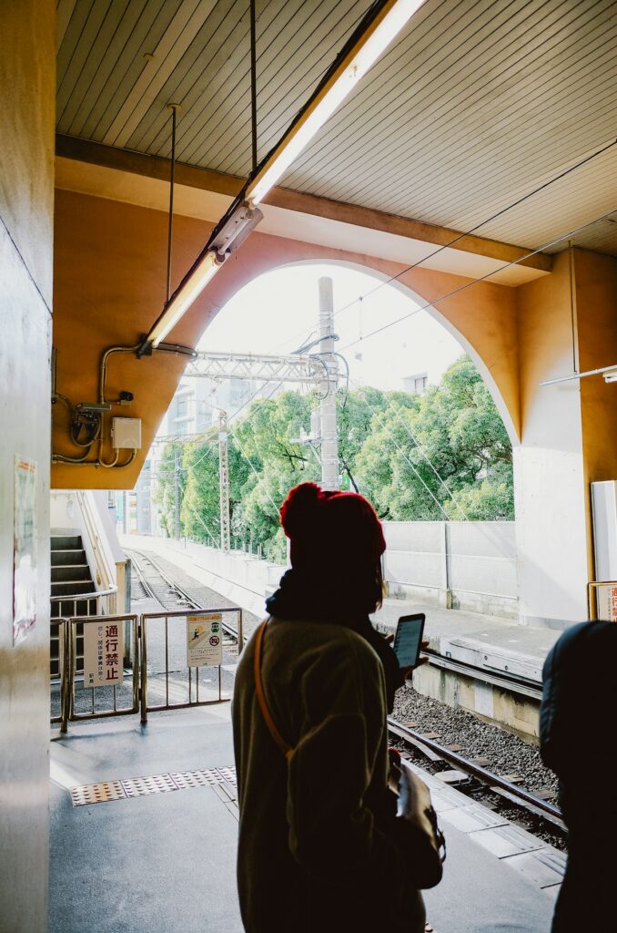 A traveler checks his phone while waiting on a train platform