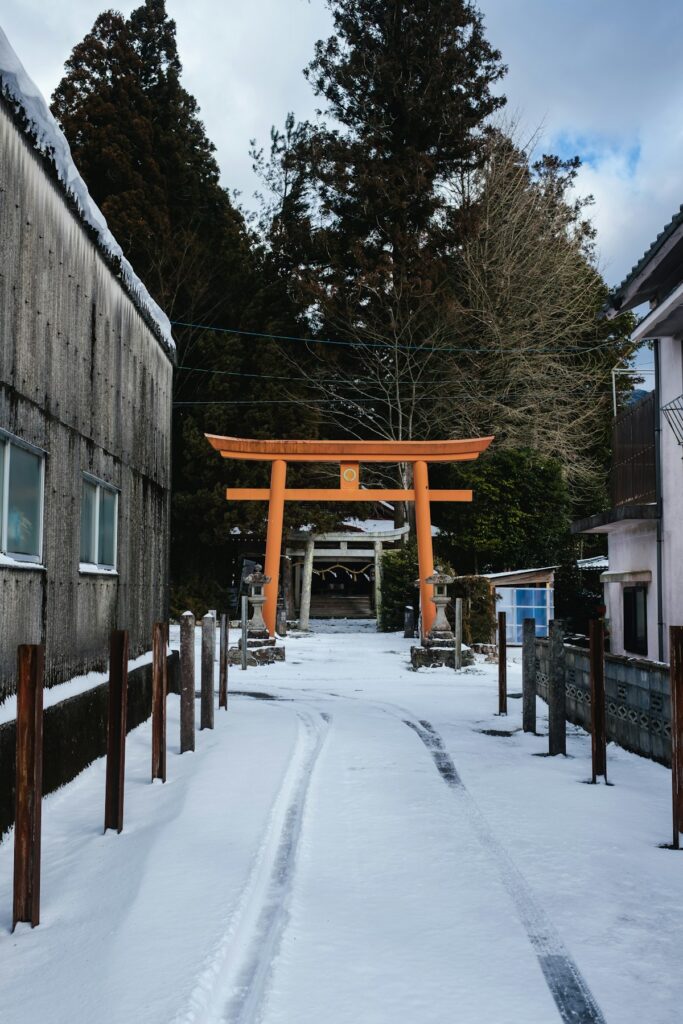 Snow blankets a street beside a large traditional wooden gate
