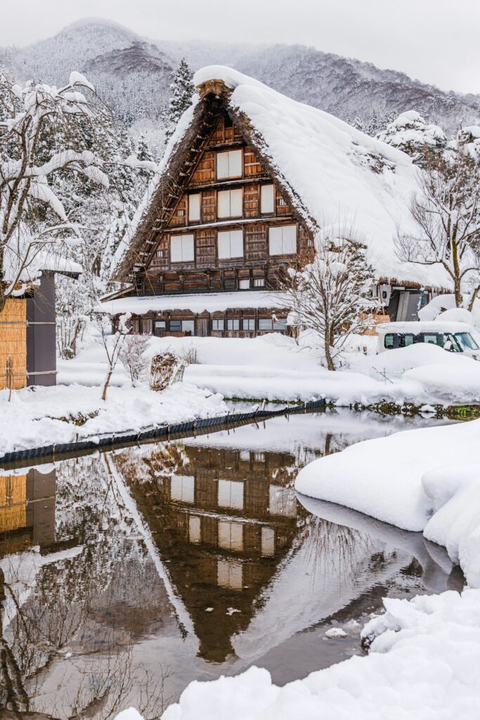 A traditional thatched-roof house sits covered in snow