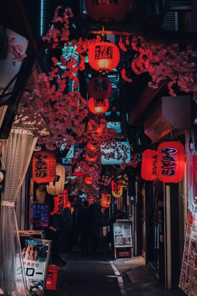People walk a street lined with glowing red lanterns