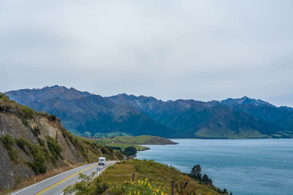 Best Internet Options for Travellers in New Zealand (2026) 12 scenic road running beside a lake and mountains