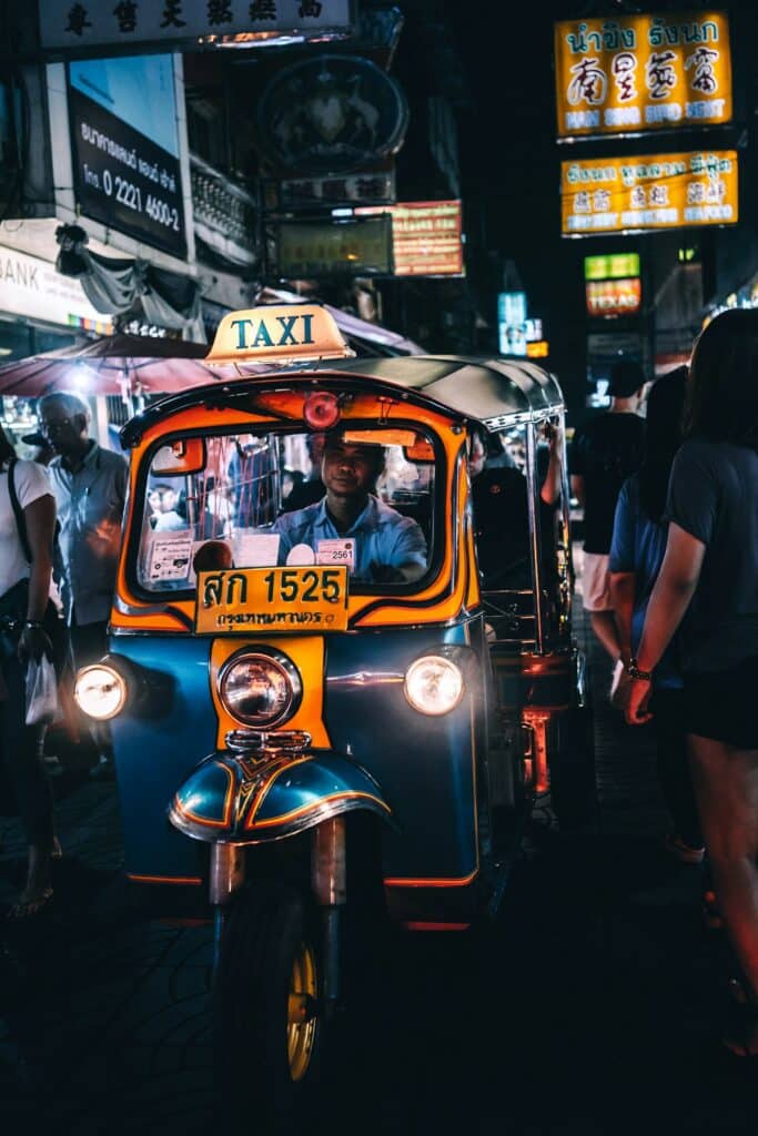 Tuk-tuk driver navigating a crowd in Bangkok's Chinatown