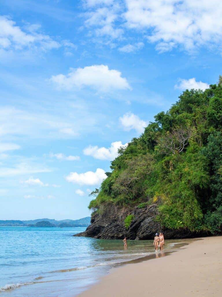 Where to Go in Southeast Asia in Summer: Best Destinations by Month 2 Travelers walking barefoot along a quiet Southeast Asian beach