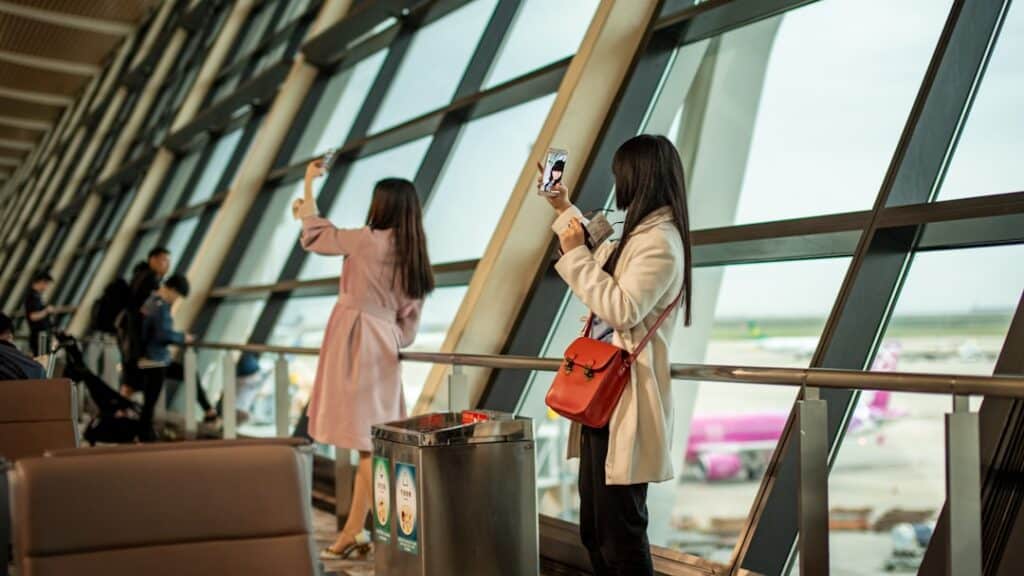 Two travelers taking selfies at an airport terminal