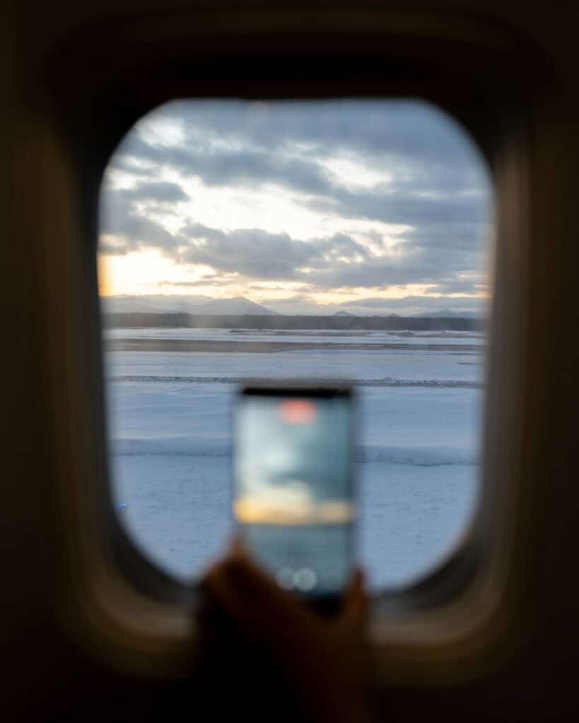 Traveler holding a phone to record the view from an airplane window